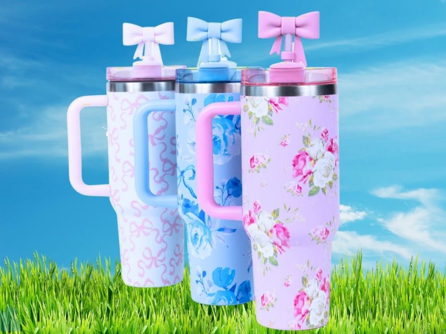 floral tumblers with handles and bow straw covers on grass