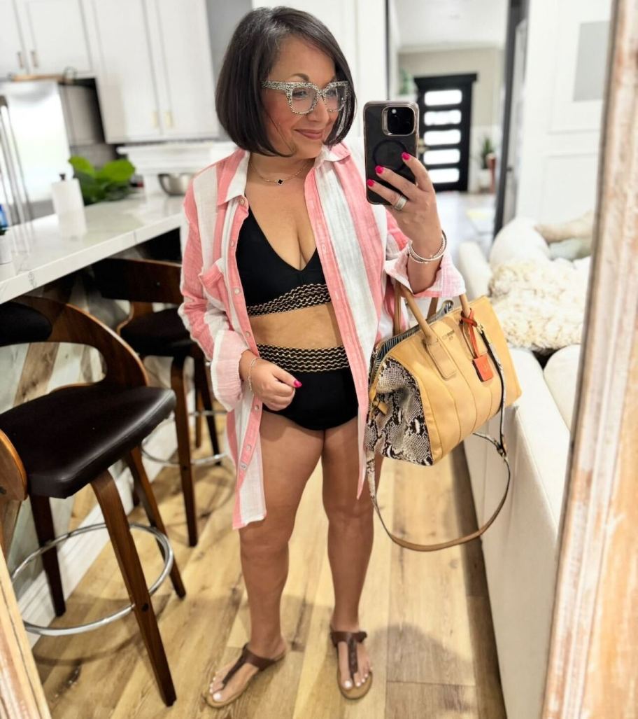 woman taking mirror selfie wearing black bikini and stripe pink and white shirt