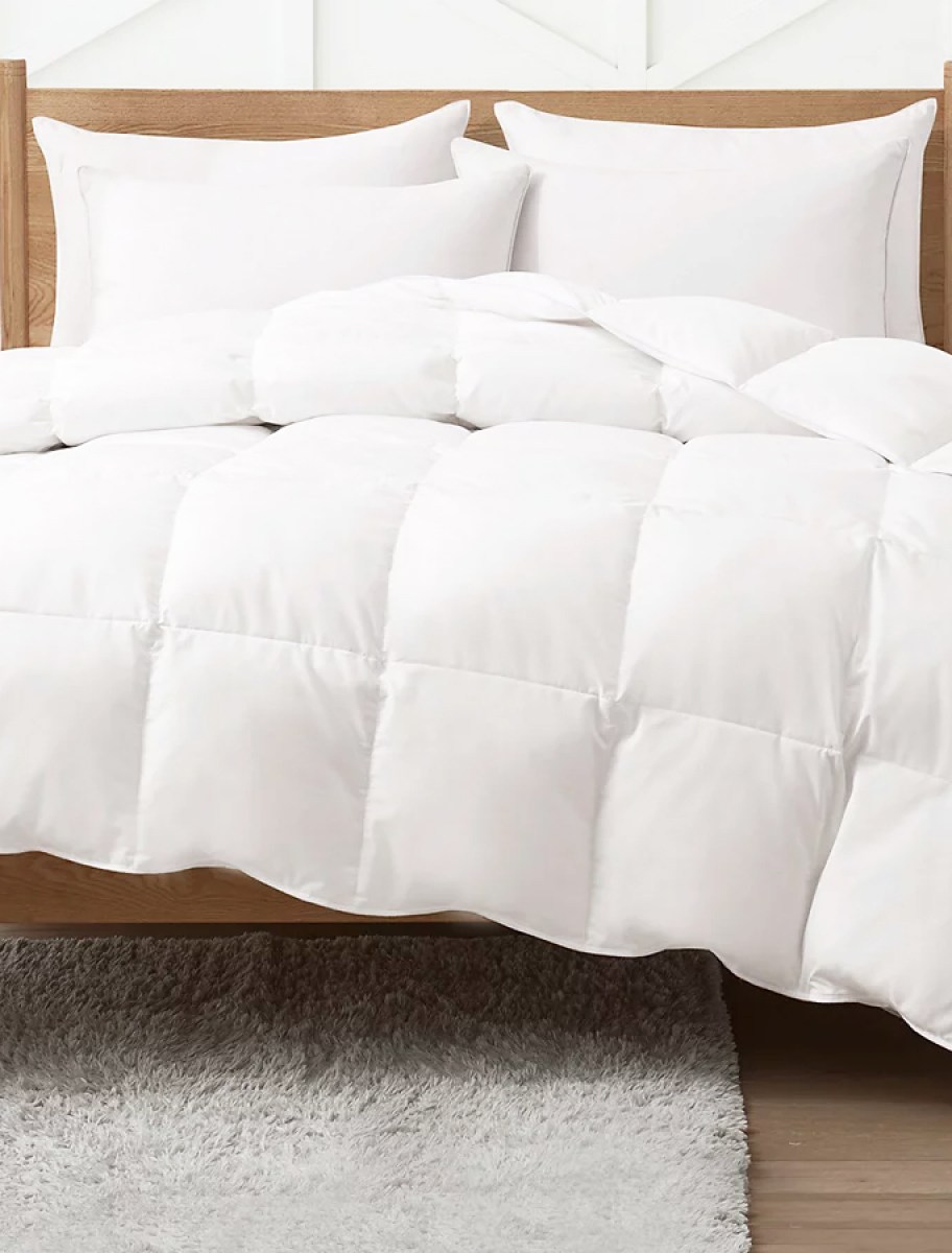 white down comforter on a bed with white pillows and sheets