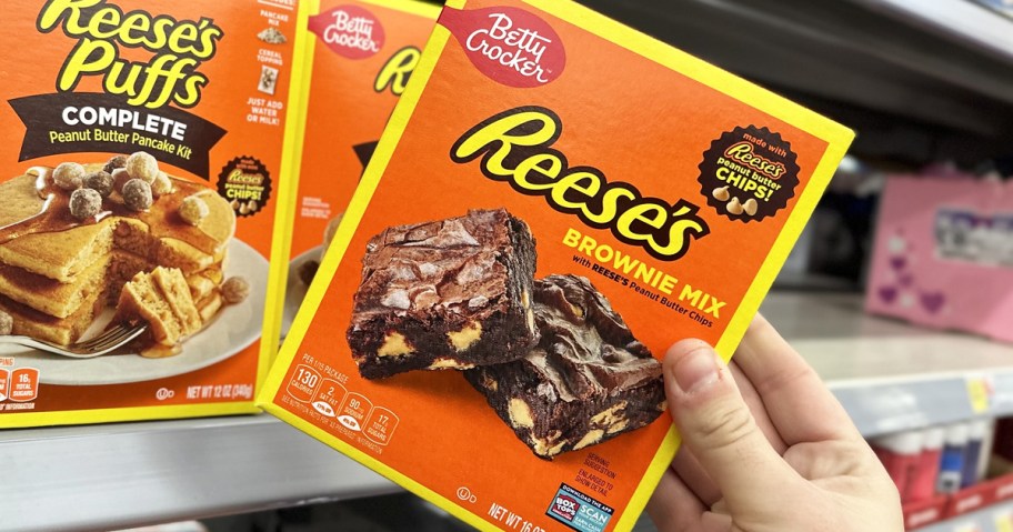 hand grabbing an orange box of Reese's Brownie Mix from store shelf