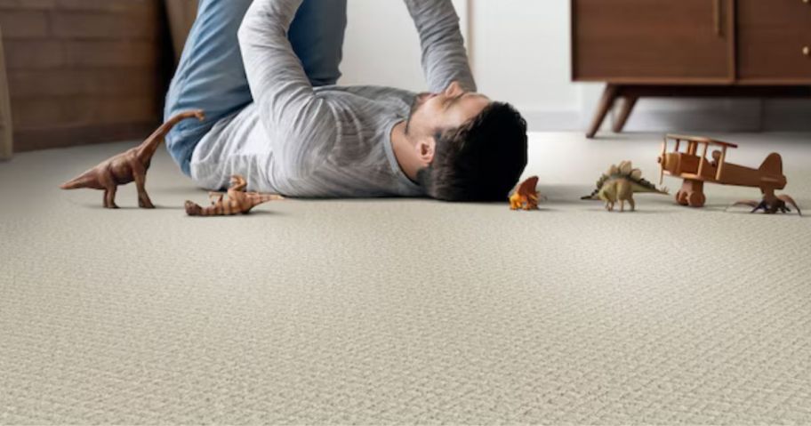 A man playing with a child on a beige carpet