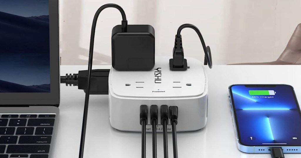White power strip with black USB cords and black plugs, charging computer and phone