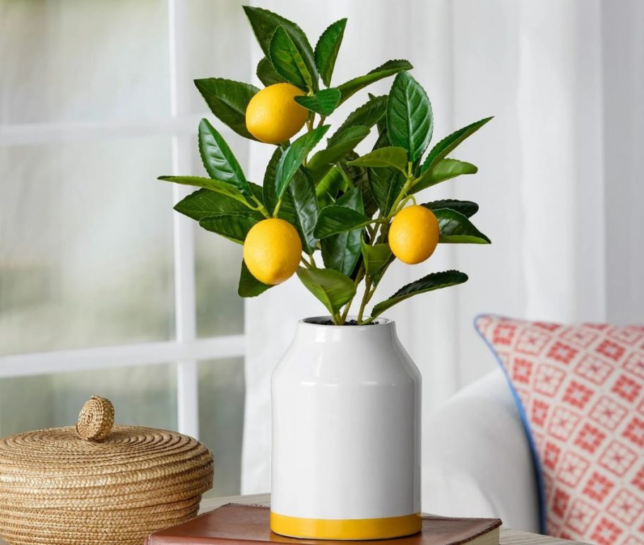 A ceramic vase with a faux lemon tree in it