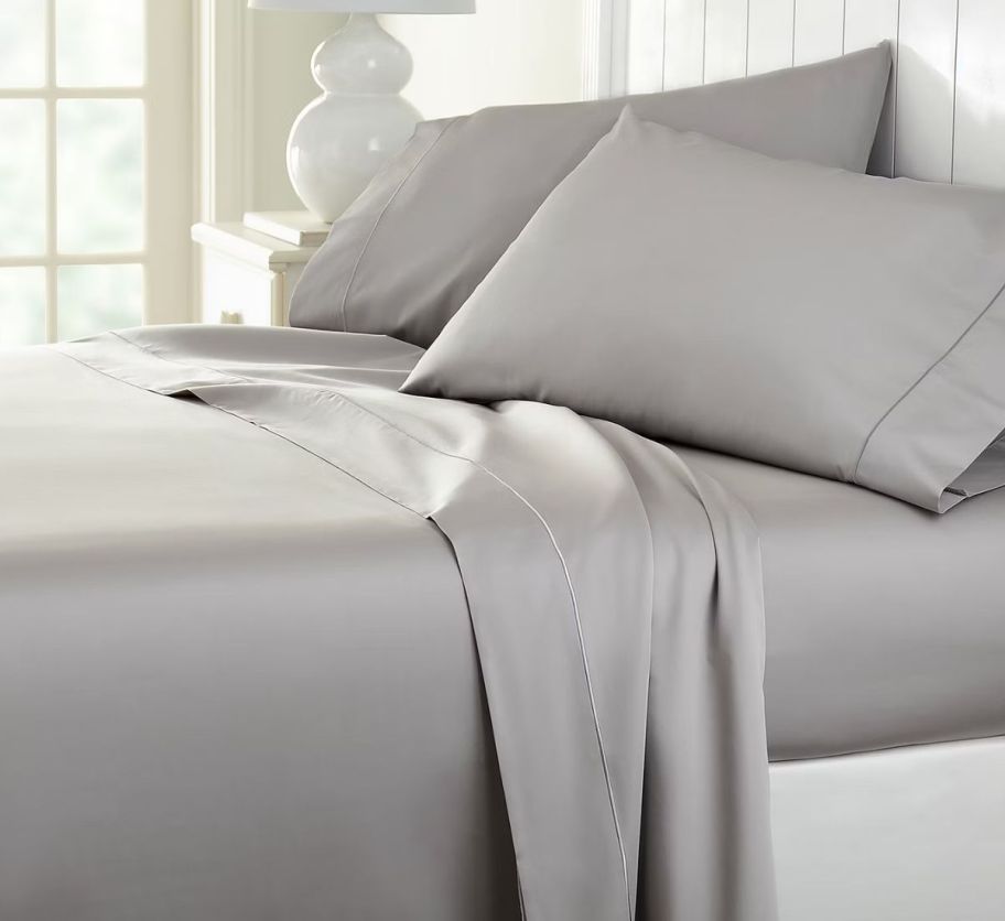 a bed made with a set of light gray sheets