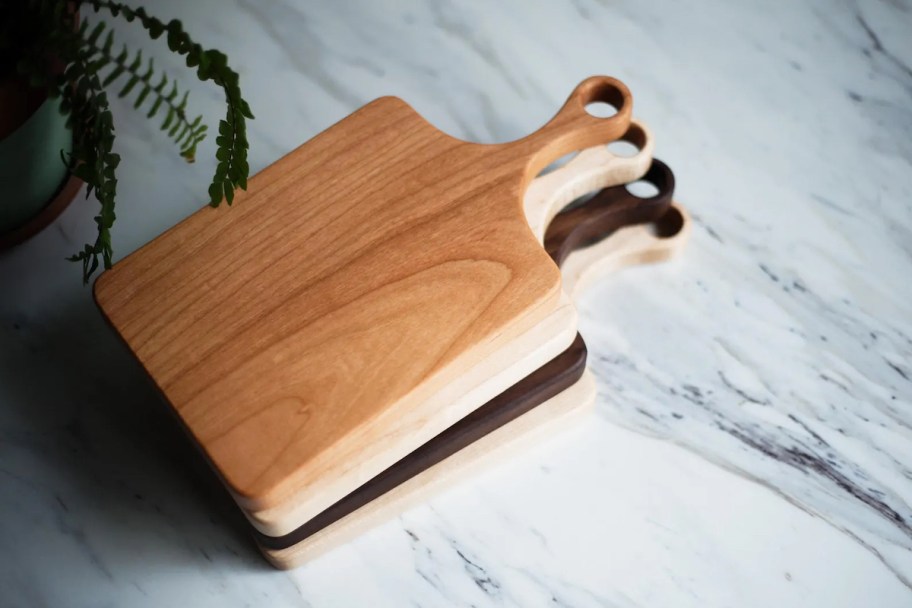 stack of different finishes of wood cutting boards on countertop