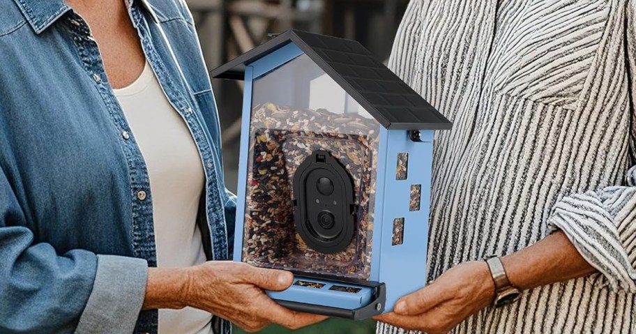 two women holding a blue smart bird feeder