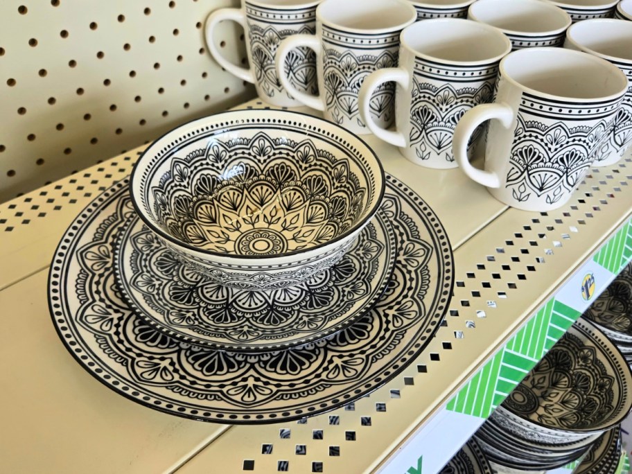 serving ware plates, bowls and mugs in a black and white medallion print on a store shelf