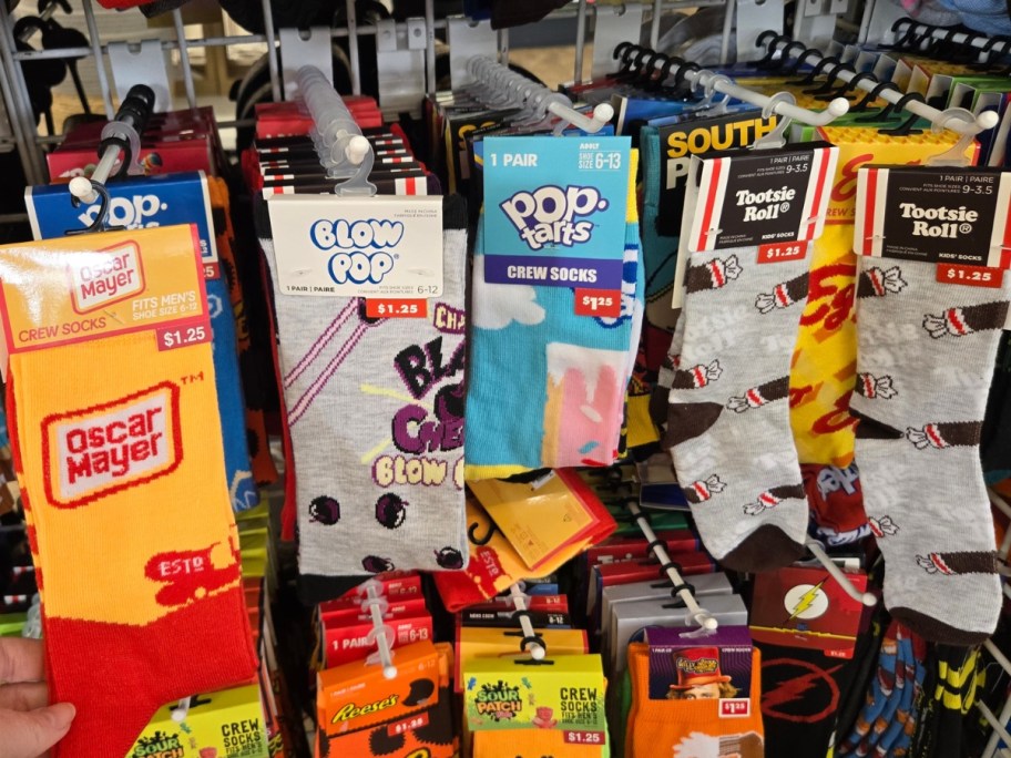 hand holding a pair of Oscar Mayer socks, more food-themed socks behind it on a store rack