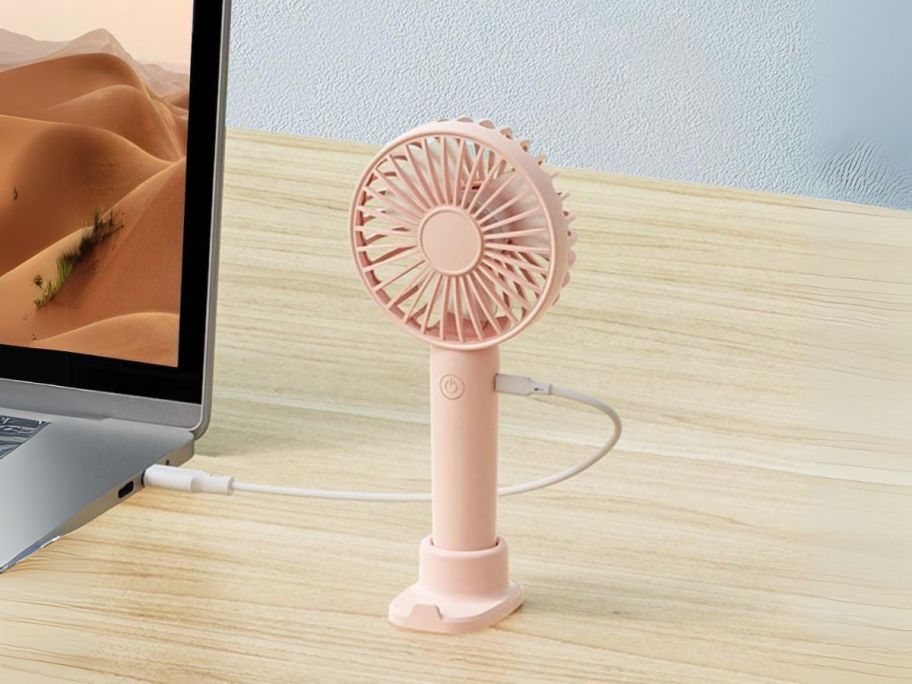 pink Rechargeable Portable Handheld Fan on table plugged into laptop