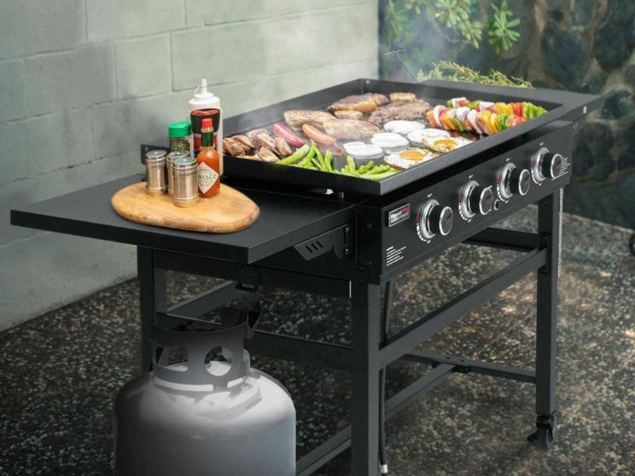 Royal Gourmet 35" 4-Burner Propane Gas Grill Griddle in yard with food being cooked on it