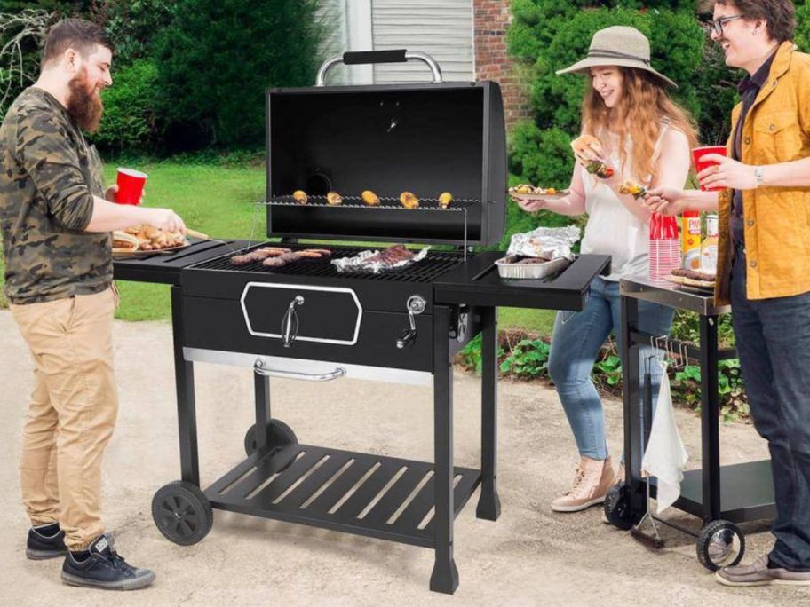 people gathered around Royal Gourmet 30" Charcoal Grill with a man cooking on it