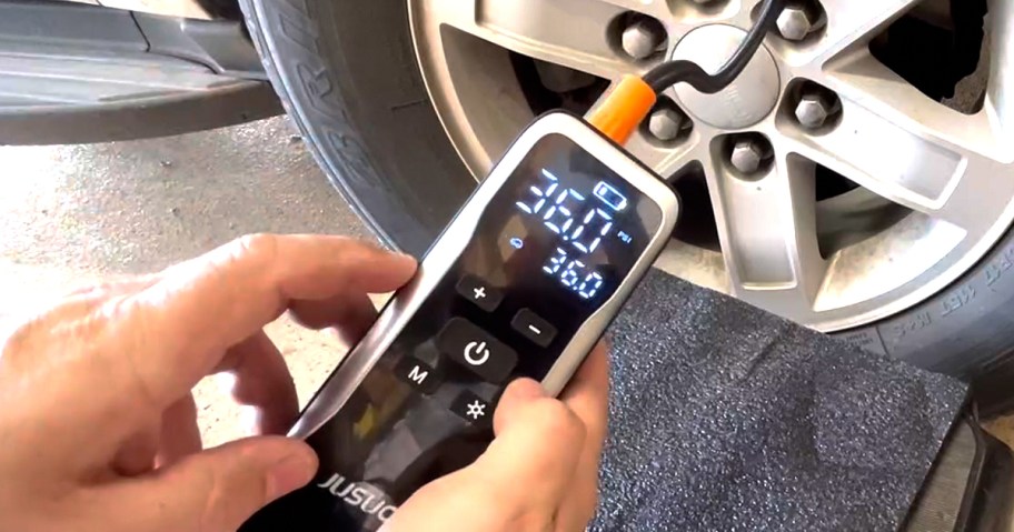 hand holding a portable tire inflator air compressor