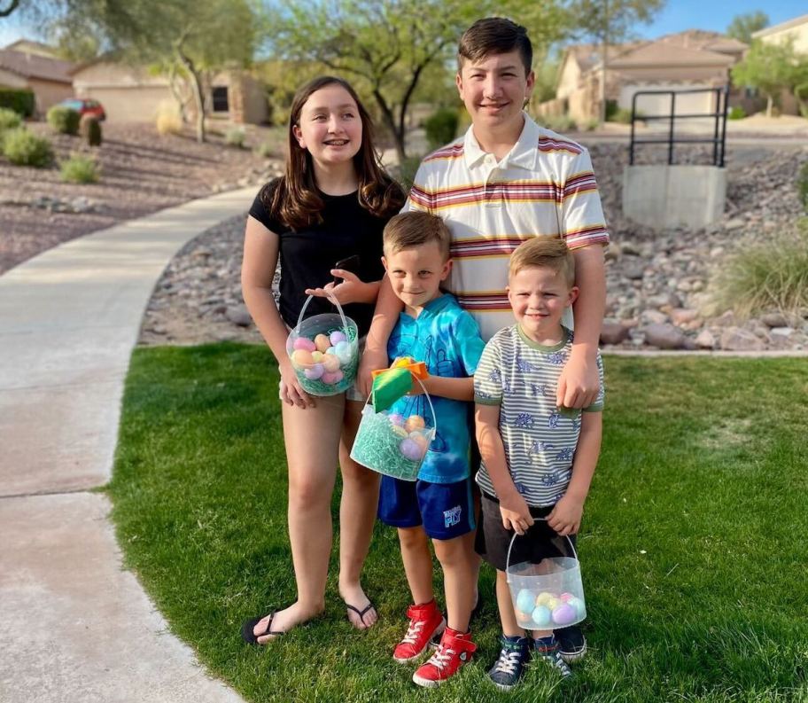 kids standing in grass holding easter baskets and eggs