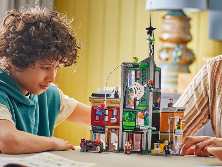 kid playing with LEGO Spider-Man vs. Oscorp on table