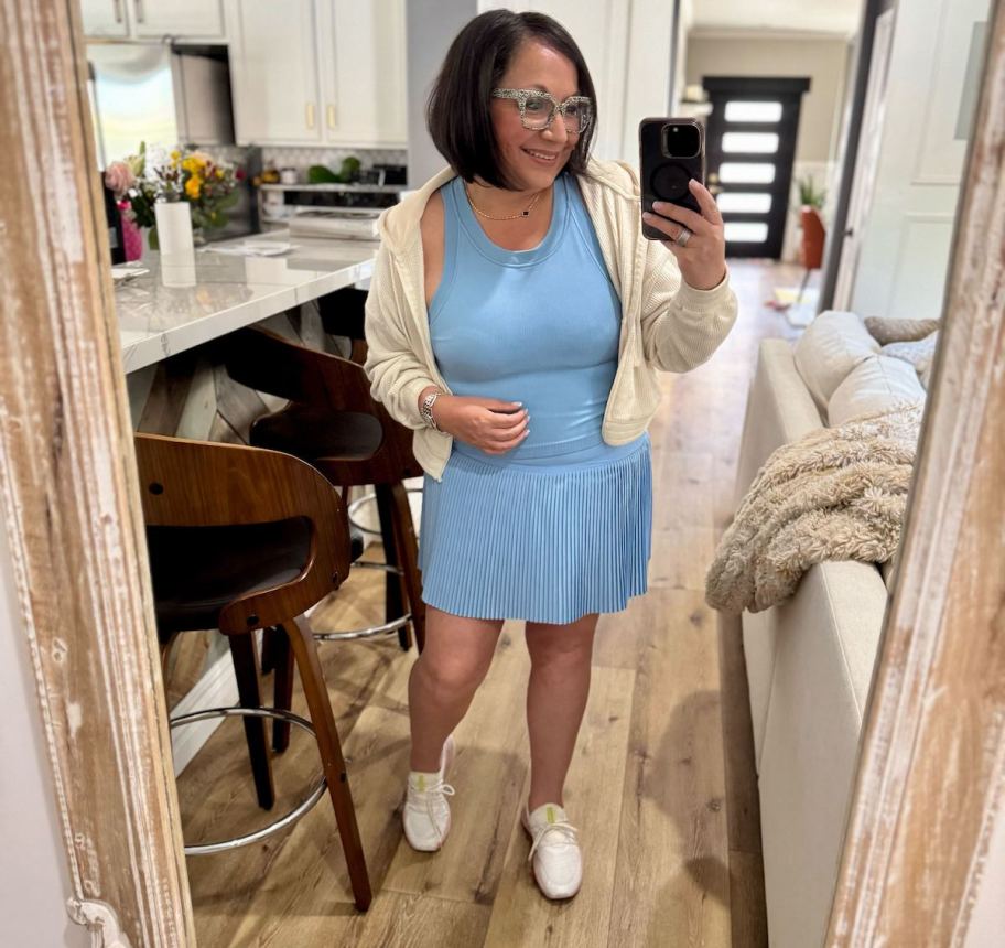 woman taking mirror selfie wearing blue tennis outfit