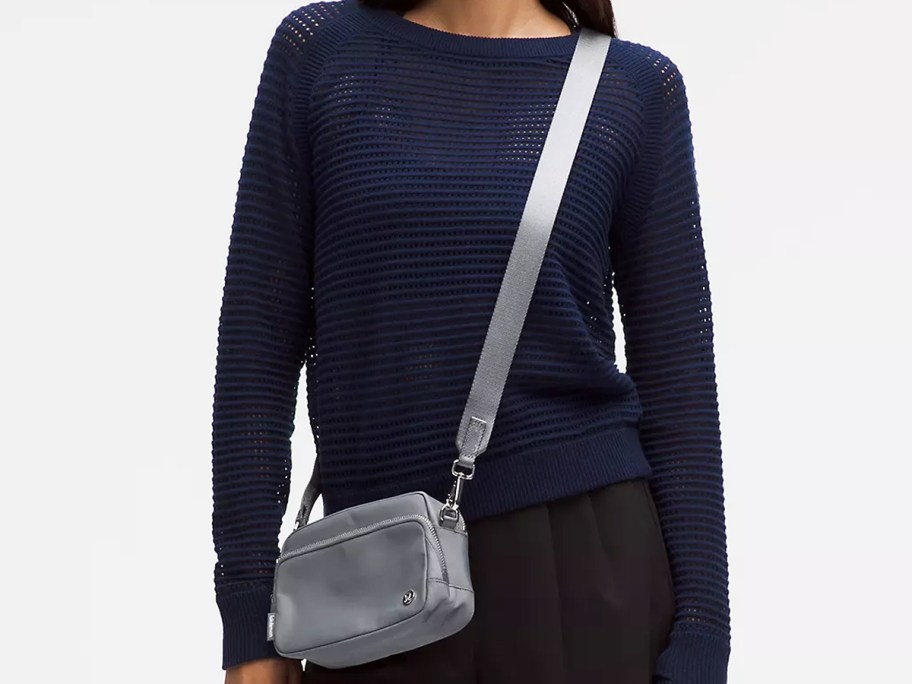 woman in a navy sweater with a silver crossbody bag