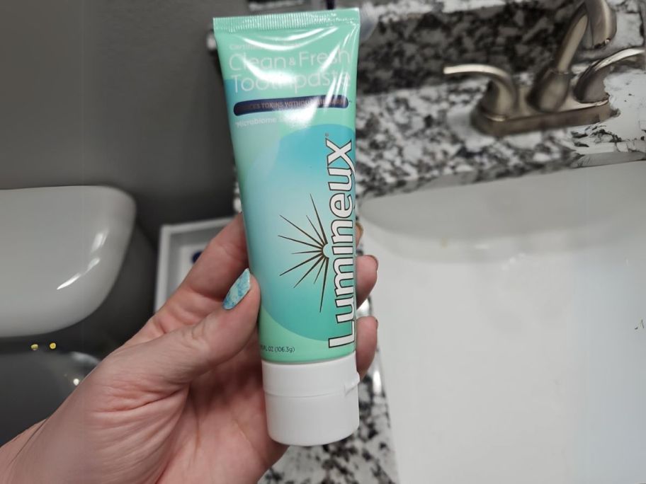 Lumineux Complete Care Toothpaste 3.75oz in hand in bathroom