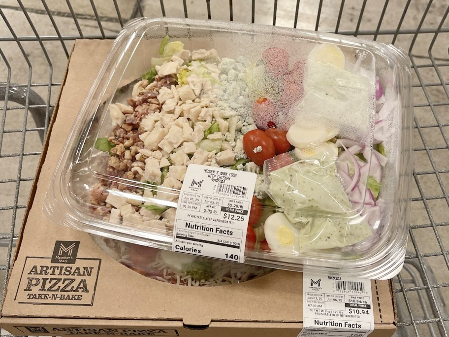 cobb salad container sitting on box of pizza
