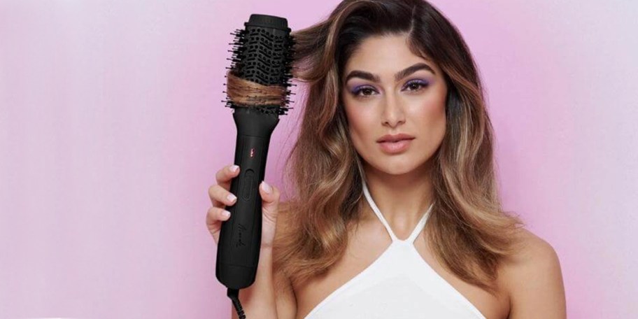 woman holding black blow out brush in hair