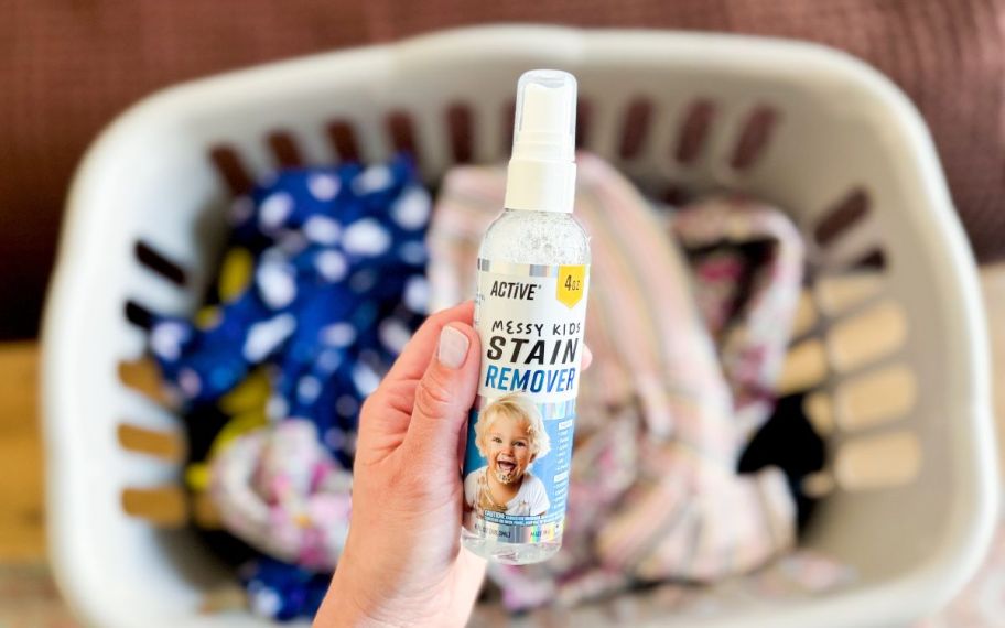a womans hand holding a bottle of stain remover spray