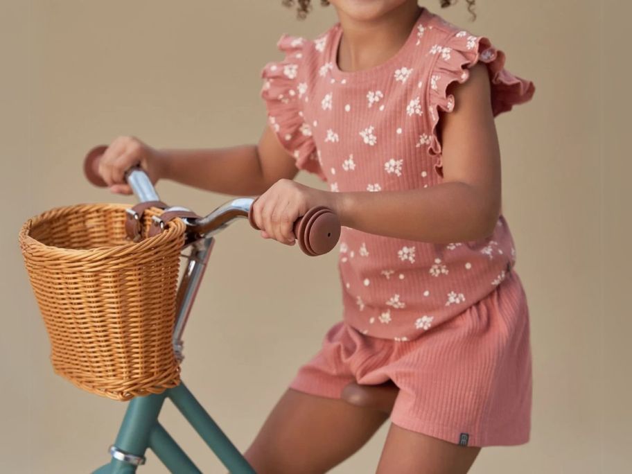 girl on bike wearing modern moments by gerber pink outfit with flowers on it