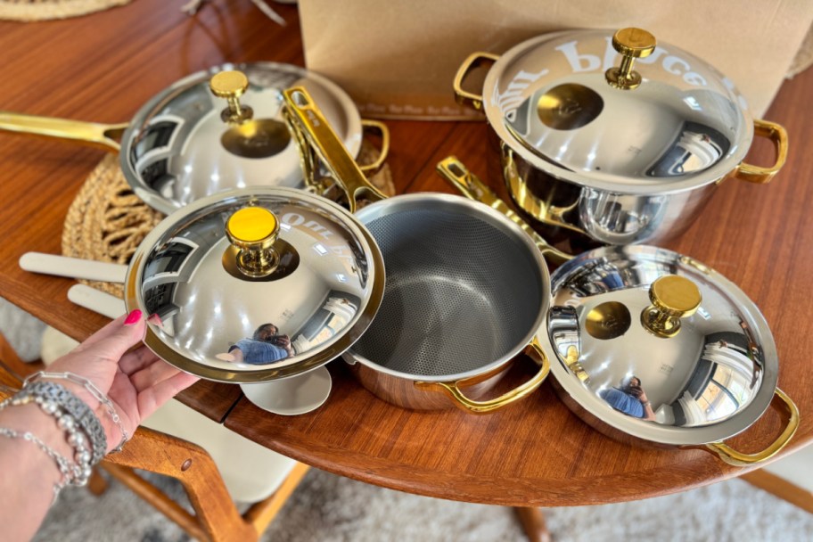 hand holding titanium pots and pans with gold details