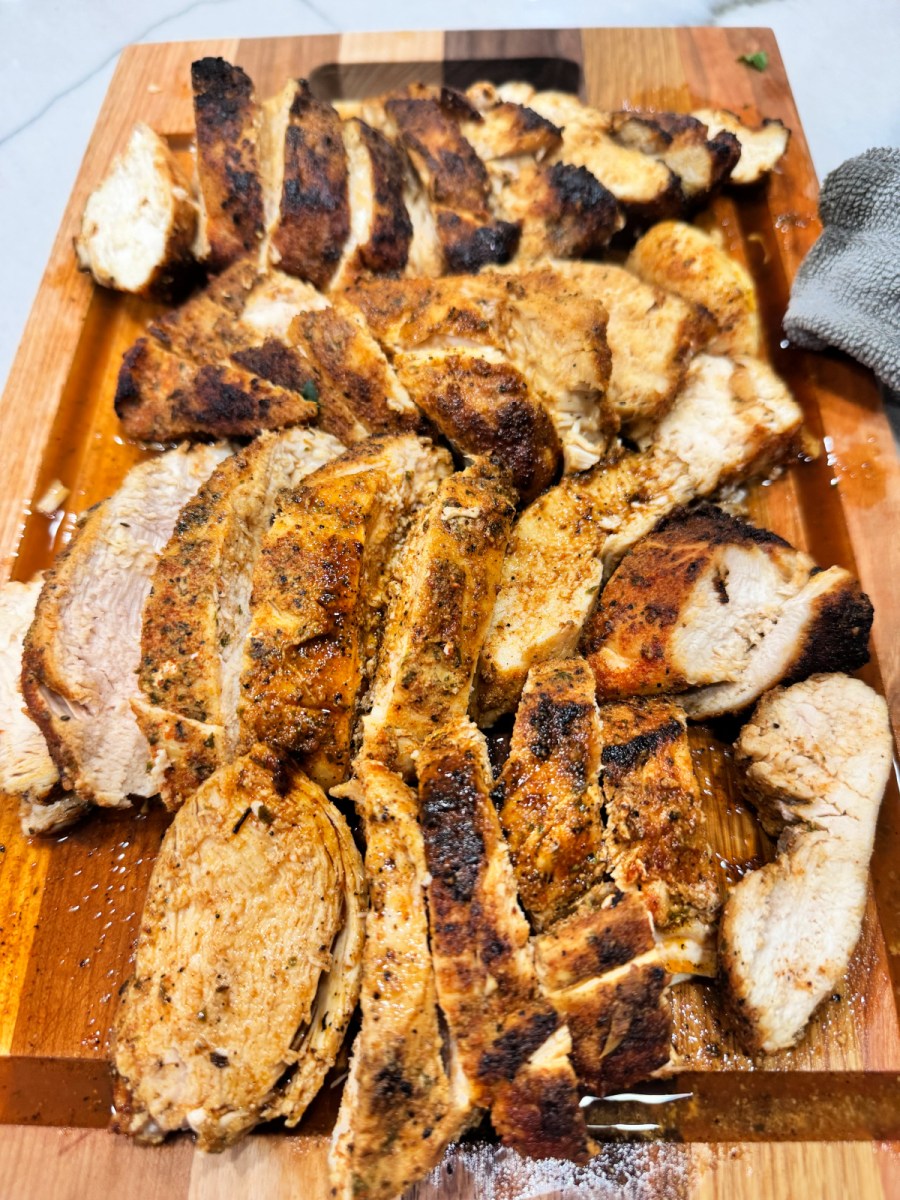 seasoned cooked chicken breast meat sliced on a cutting board