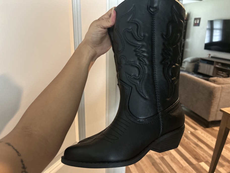 hand holding up black cowboy boots