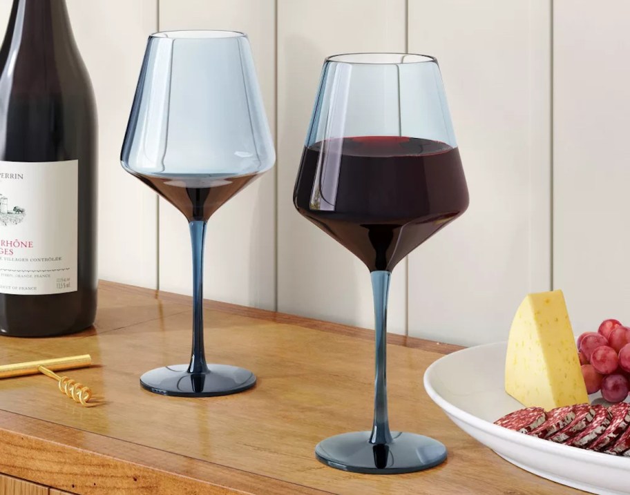 blue stemmed wine glasses on wood console table