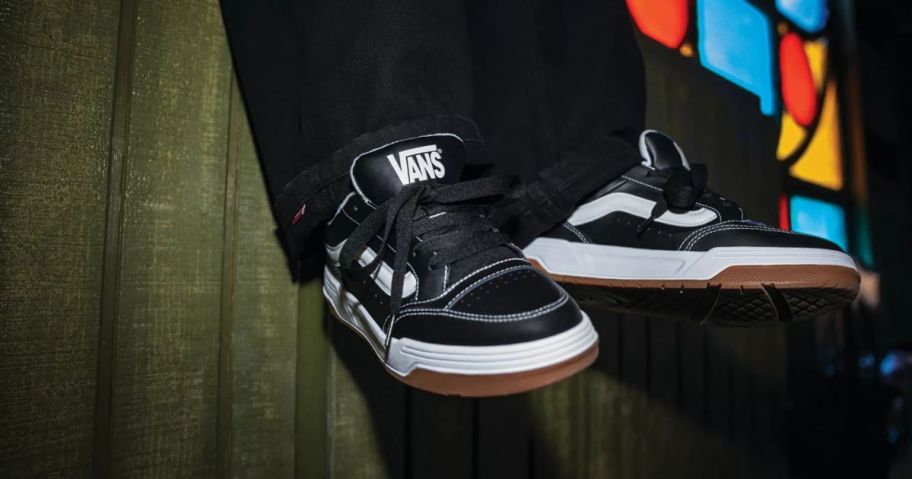 man wearing black and white vans shoes with stain glass window in the background