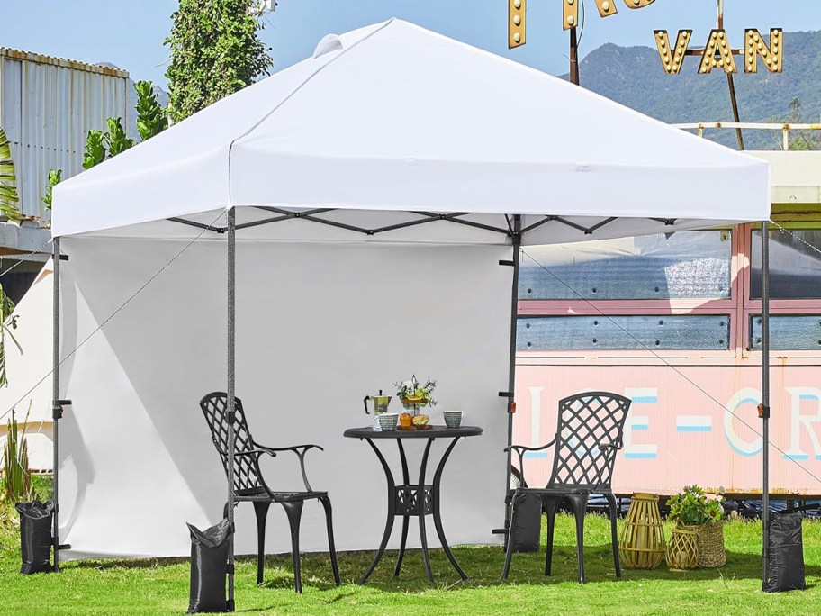 white pop up tent outdoors with table and chairs underneath it