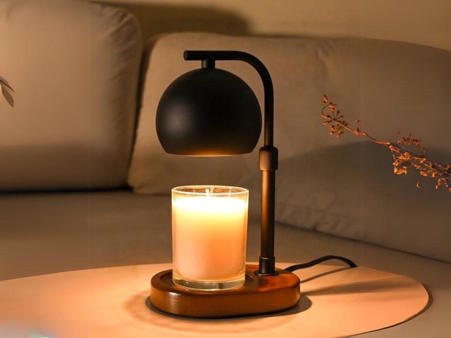 a black candle warmer lamp with a candle on a coffee table