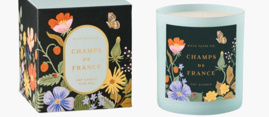 a large candle with a floral front next to the decorative box it comes in