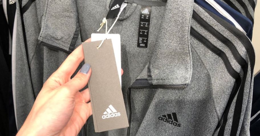 Hand holding the tag on an adidas jacket