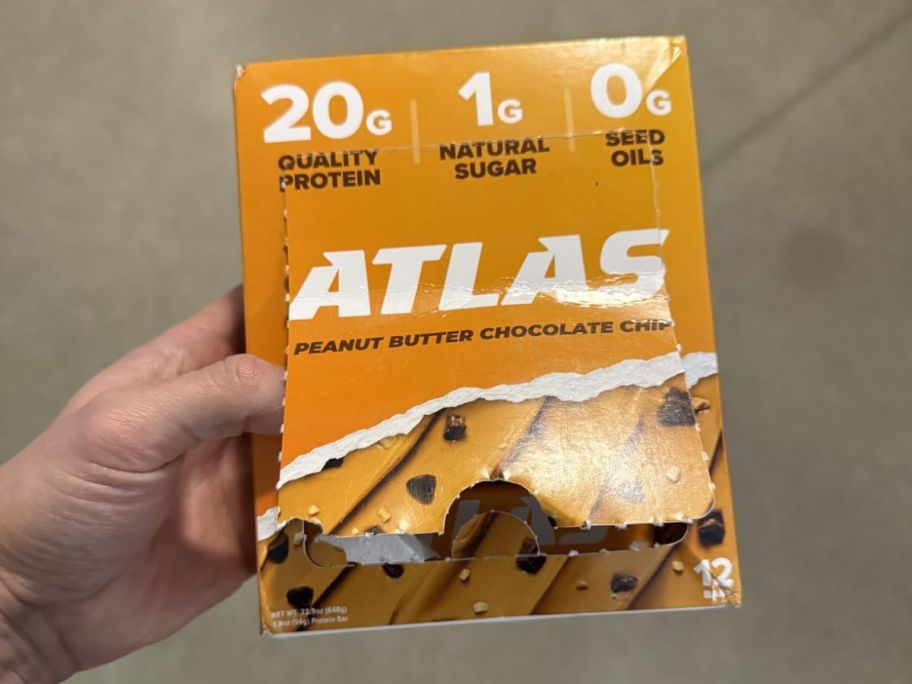 A person holding a box of Atlas Peanut Butter bars