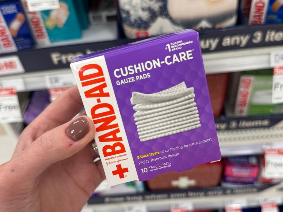 a womans hand holding a box of band aid gauze pads