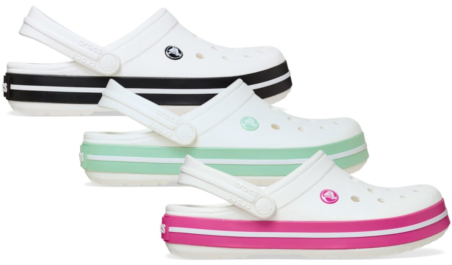 Crocs Adult Crocband Clogs in white with black, mint green, or pink stripe accents, featuring ventilation holes, heel straps, and sporty sidewall bands.