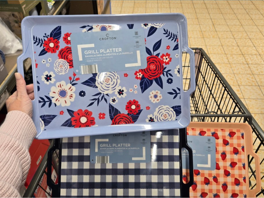 hand holding a floral grill platter with 2 more options displayed inside of an ALDIs cart