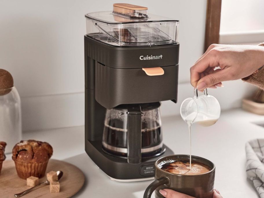 A Black Cusinart Soho Collection Coffee maker on a counter next to a cup of coffee