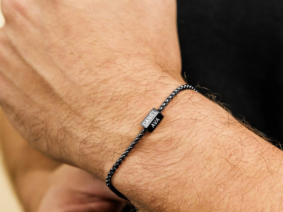 man wearing a black bracelet with kids names on a bead