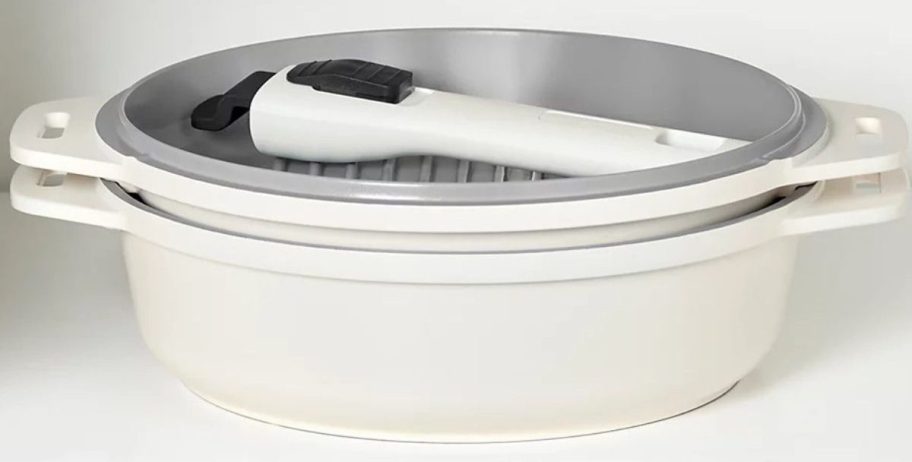 A Dash SmartStore 5-in-1 Cookware Set nested in a cabinet