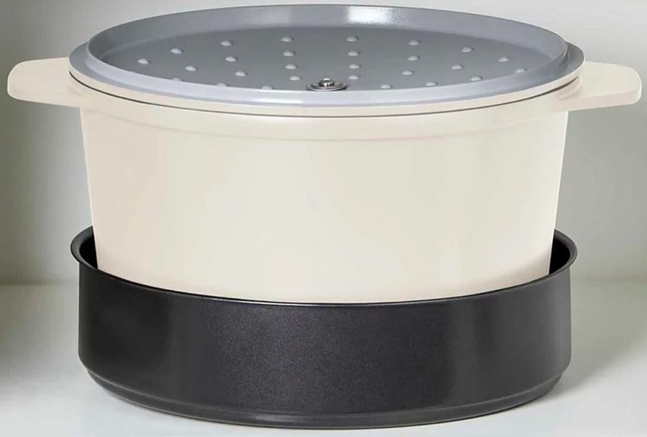 A Dash SmartStore Ceramic 5.8qt MultiPot & Steamer nested in a cabinet