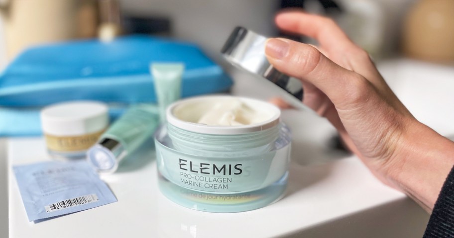 hand taking the lid off a jar of ELEMIS Pro-Collagen Marine Cream