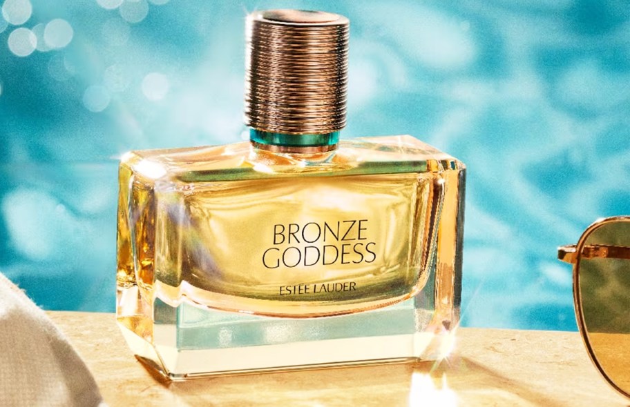 yellow bottle of Estée Lauder Bronze Goddess Eau Fraîche Eau de Toilette near sunglasses