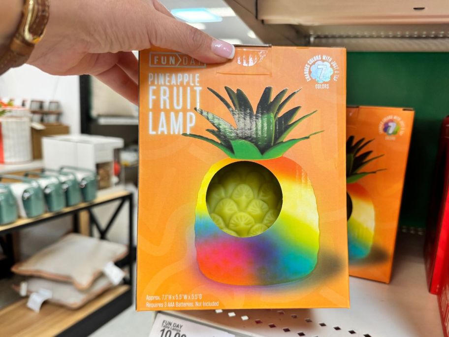 A woman displaying a squishy yellow pineapple lamp at Target
