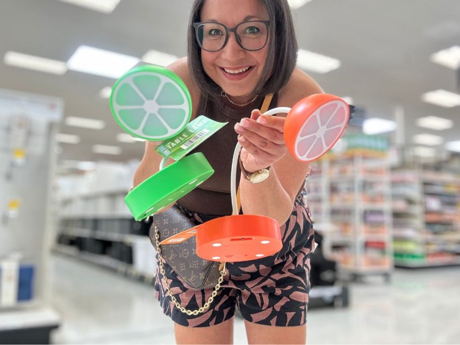 A woman holding two fruit-shaped lamps at Target