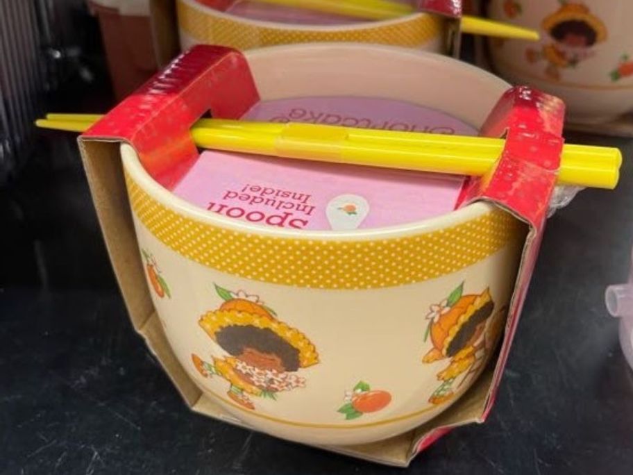 A small bowl with cartoons on it and chopsticks on the top
