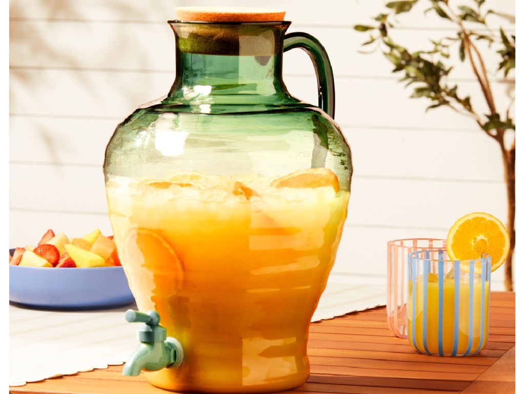 Green tented glass dispenser on picnic table next to lemonade