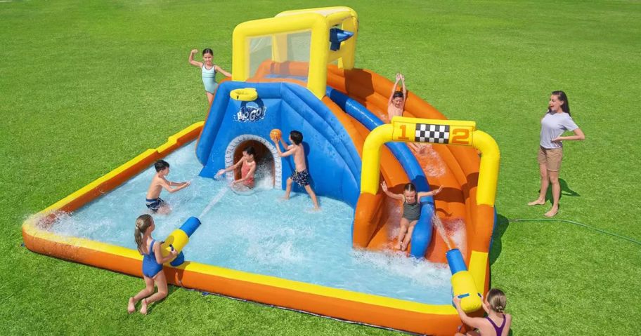 Kids playing on a large inflatable water park 