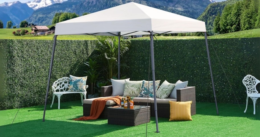 a white pop up canopy tent in a backyard with patio furniture under it